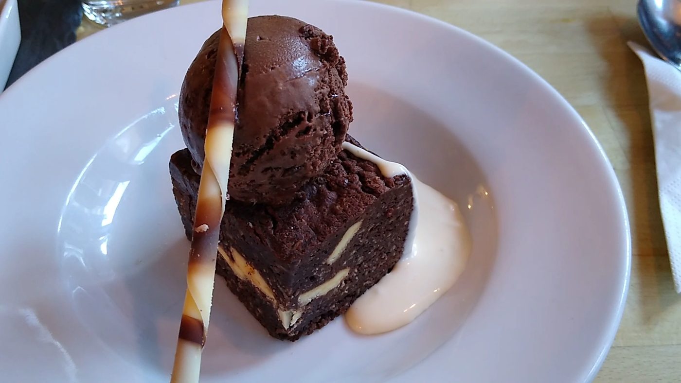 A chocolate dessert with ice cream and a wafer
